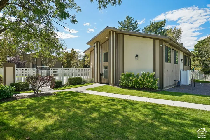 Modern architectural home featuring a clean-lined exterior with vertical metal accents and cream-toned siding, set on a manicured lawn with mature landscaping