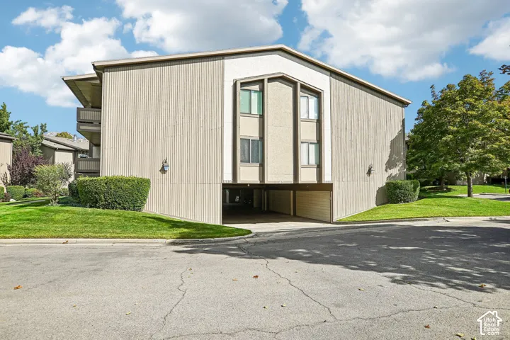 Multi-story building with vertical siding, a central architectural feature with multiple windows, and a covered parking area