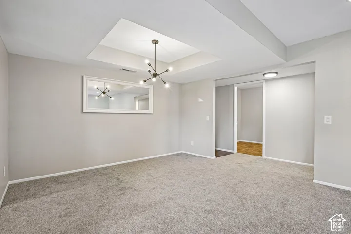 Spacious primary living area showcasing neutral wall finishes, recessed ceiling with skylight, modern ceiling fan fixture, and plush carpeting throughout