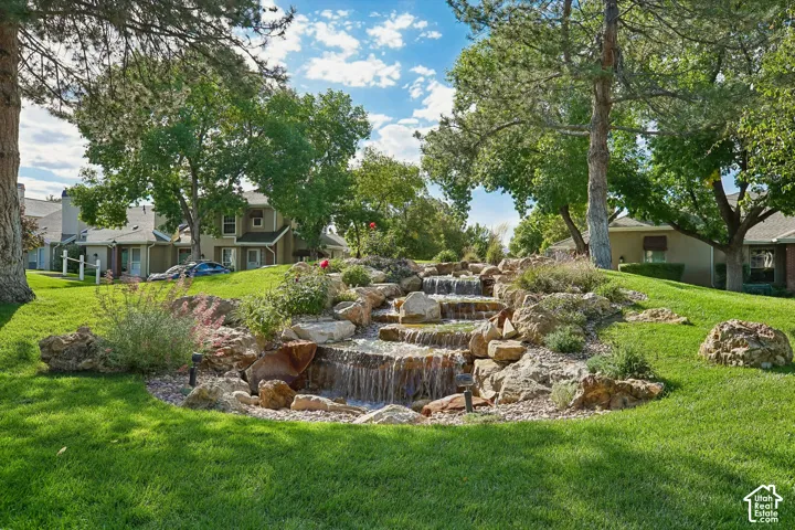Expansive backyard oasis featuring a tiered water feature with cascading stone construction, mature landscaping with native plantings, and manicured lawn