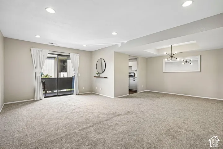 Recessed ceiling lighting, tray ceiling, modern chandelier, sliding glass door, and neutral wall colors