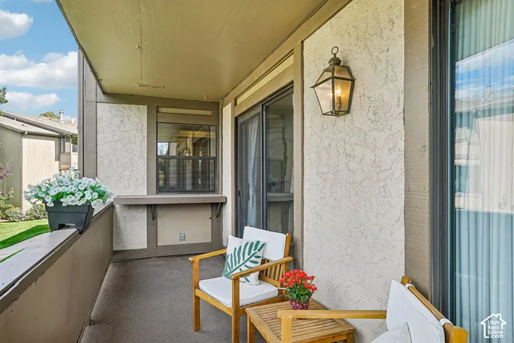 Exterior balcony featuring textured stucco siding, a built-in shelf, and an overhead lantern-style light fixture