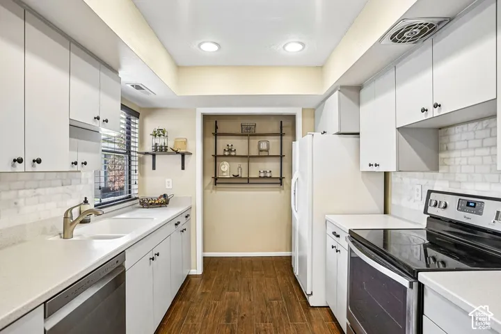 Galley kitchen featuring white cabinetry with hardware accents, quartz countertops, subway tile backsplash, and stainless steel appliances including a gas range and under-counter sink