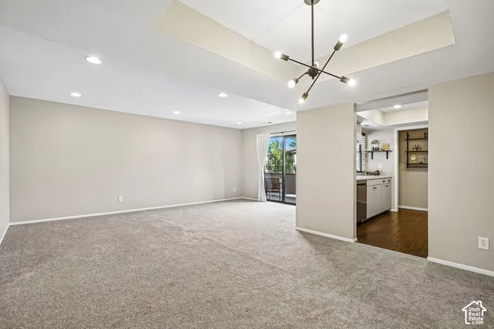 Spacious room featuring neutral carpeting, recessed lighting, and a modern chandelier