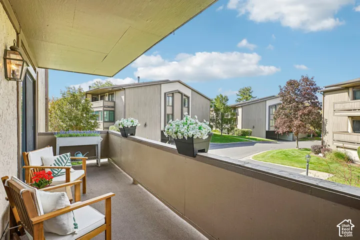 Private balcony featuring an exterior light fixture and surrounding landscape with mature trees