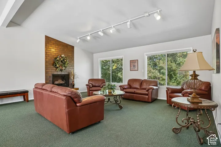 Spacious living area featuring a brick fireplace, track lighting, and two large windows