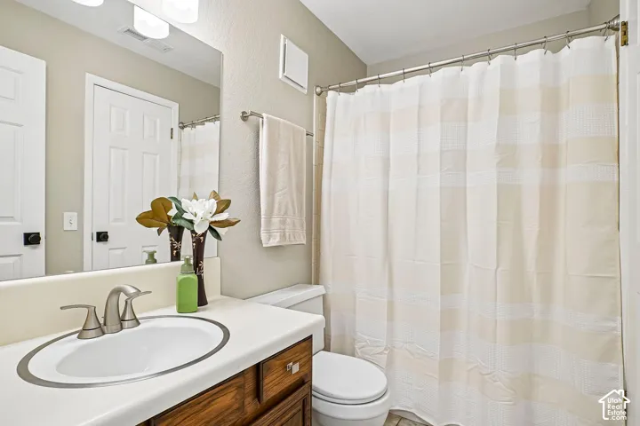 Bathroom featuring a vanity with an integrated sink, brushed nickel faucet, wood-finish cabinetry, and a full-width wall mirror