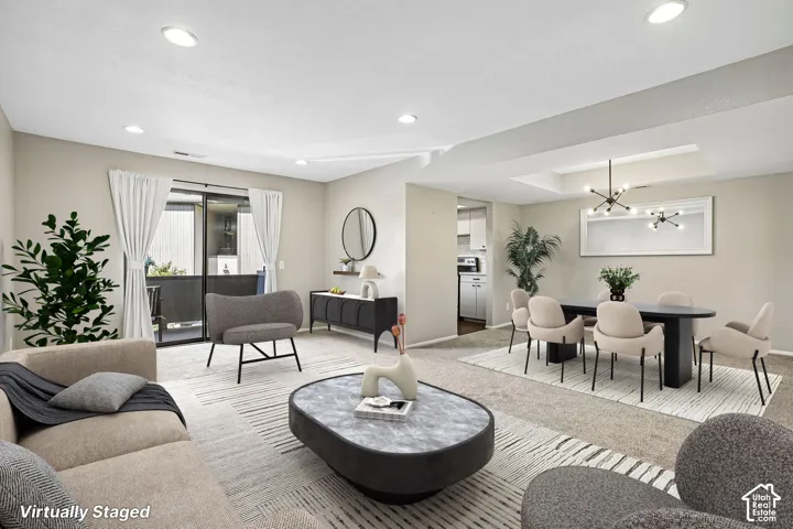 Recessed lighting, sliding glass door, and a dining area with a tray ceiling and contemporary chandelier