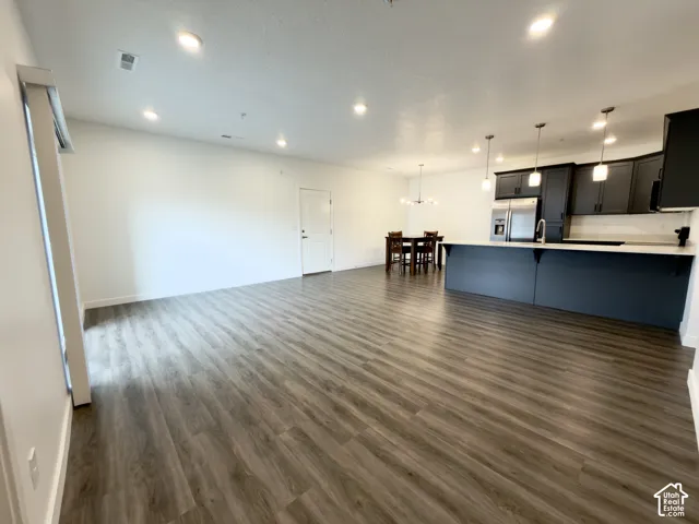 HUGE, open family room with LVP flooring, recessed lighting, a kitchen island with pendant lights, and grey/blue cabinetry