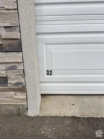 White paneled garage door with address numbers and stacked stone veneer