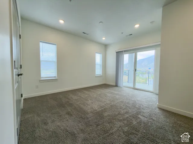 Primary bedroom with lots of windows, recessed lighting, white trim, and a glass sliding door opening to a large balcony