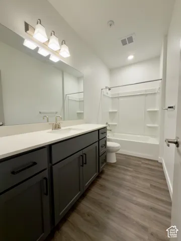 Spacious hall bathroom featuring a dark wood-finish vanity with a light countertop, a built-in shower and tub combination, and LVP flooring
