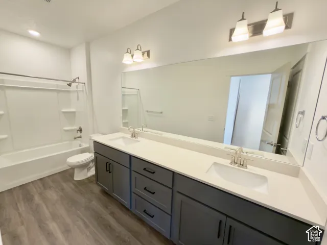 Primary bathroom with double vanities with gray/blue cabinetry, expansive mirror, and a full bathtub with an integrated shower