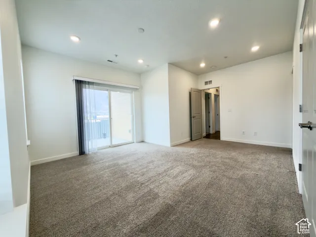 Primary bedroom featuring neutral carpeting, recessed lighting, and a sliding glass door to a large balcony with unreal mountain views