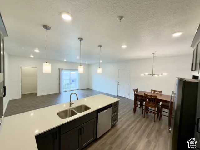 Open-concept living space featuring LVP flooring, recessed lighting, and a sliding glass door to the balcony