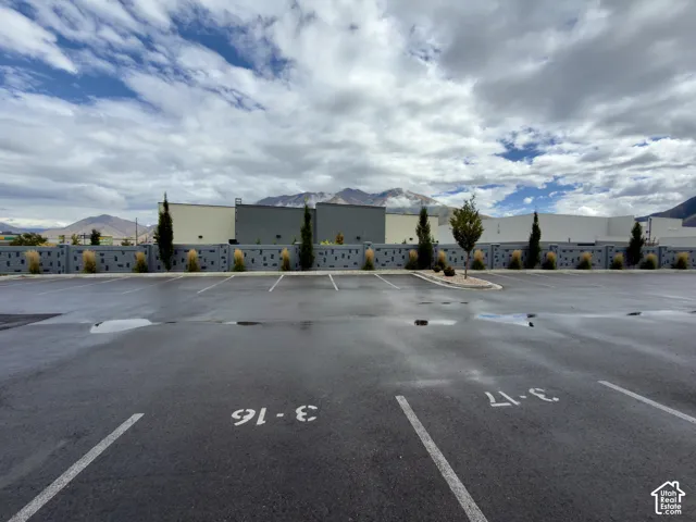 Paved parking lot for building 3 with marked spaces, bordered by a decorative block wall and planted trees