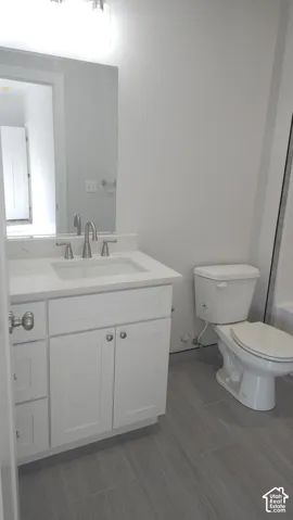 White vanity with an integrated sink and brushed nickel hardware, set against gray plank-style floor tiling