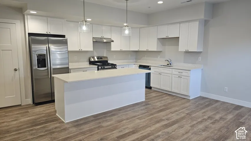 Kitchen featuring white shaker cabinetry, stainless steel appliances, a center island, recessed lighting, and wood-finish flooring