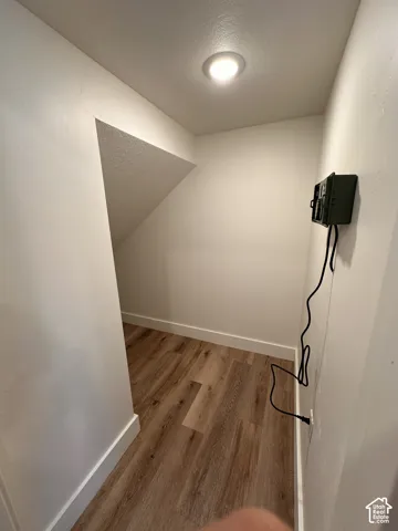 Under-stairway storage. Wood-finish flooring with white trim, recessed ceiling lighting, and a wall outlet