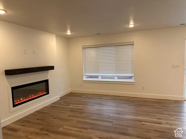 Recessed lighting, wood-finish flooring, built-in fireplace with dark wood mantle, white window blinds, and white trim throughout