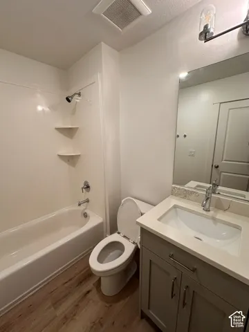 Bathroom featuring a tub/shower combination, wood-finish flooring, a vanity with an integrated sink, and a framed mirror