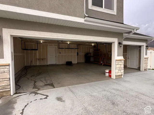 Three-car garage with overhead storage racks, interior door access, and exterior carriage lights