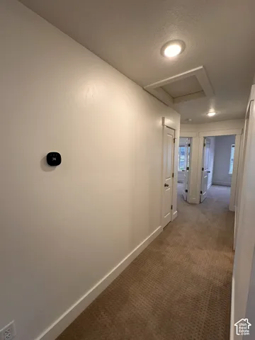 Hallway featuring recessed lighting, a modern thermostat, and textured carpeting