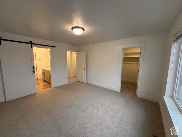 Spacious Master bedroom featuring neutral carpeting, a large window, and an overhead light fixture