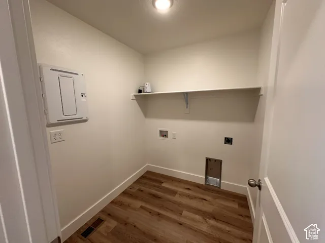 Dedicated utility space featuring wood-finish flooring, a wall-mounted shelf, and appliance hookups