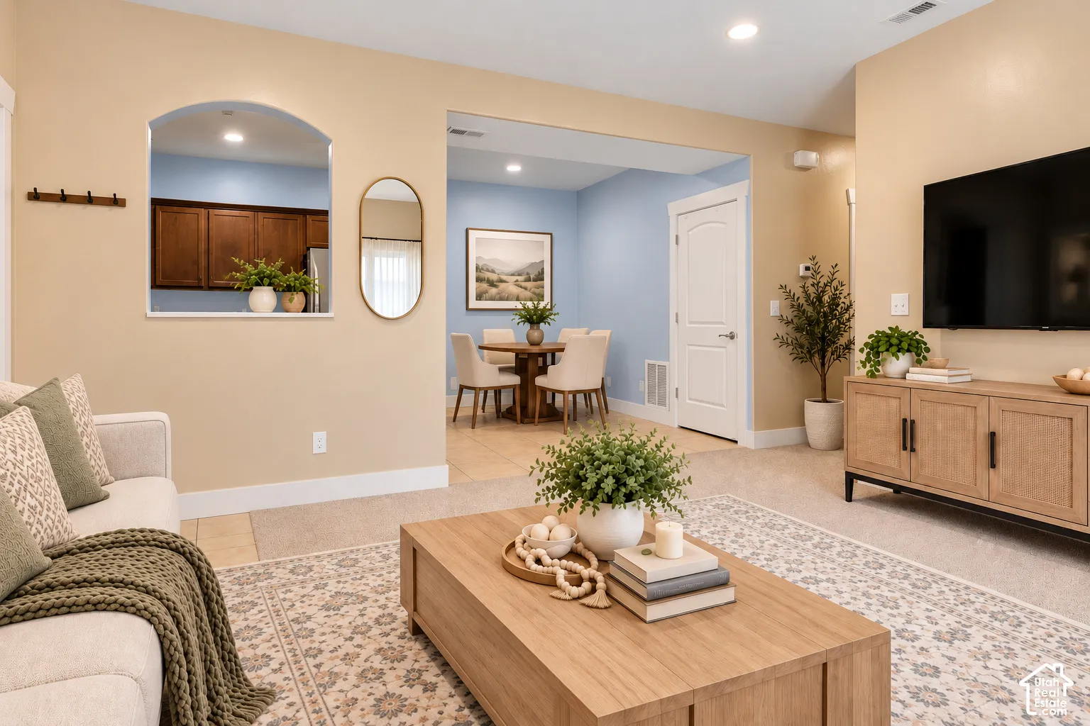 Arch pass-through window, recessed lighting, white interior door, wood-finish cabinetry, and tiled flooring