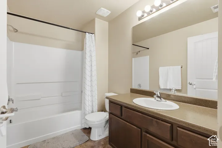 Bathroom with a built-in tub and shower combination, a dark wood-finish vanity with an integrated sink, a large wall-mounted mirror, and overhead vanity lighting