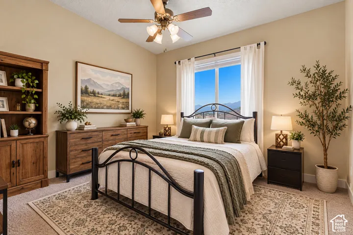 Vaulted ceiling with a ceiling fan, window with mountain scenery, and carpeted flooring