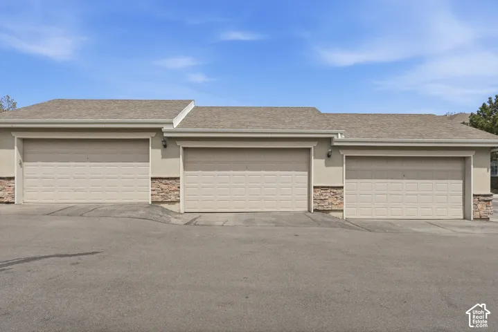 Exterior featuring three individual garage doors, each with paneled construction