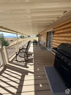 Expansive covered porch featuring a wood-finish deck, log cabin exterior, white railing, and sliding glass door access