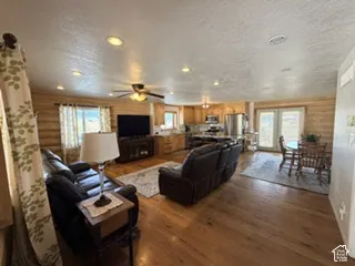 Open-concept living area with wood-finish flooring, recessed lighting, and a ceiling fan