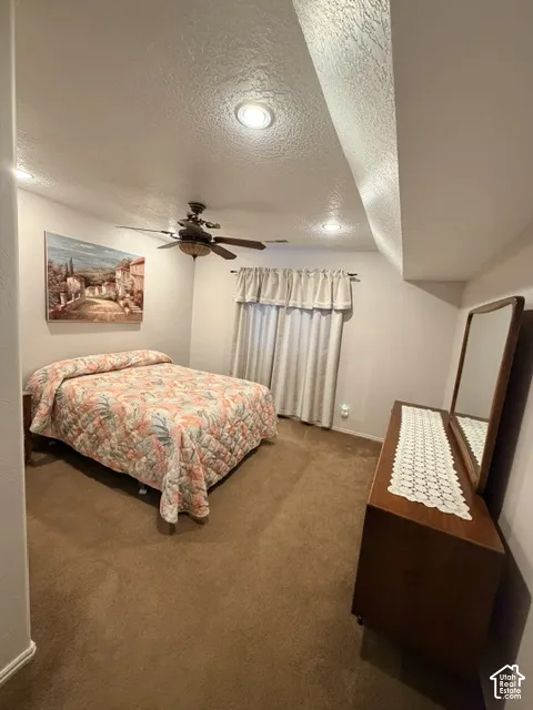 Recessed lighting with a ceiling fan, soft brown carpeting, and window with neutral-toned drapes