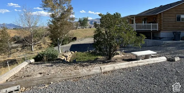Log home exterior with a white railed balcony, gravel ground cover, and a stone bench