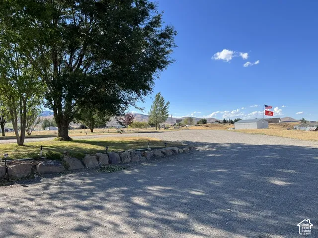 Expansive gravel lot featuring a rock retaining wall and mature trees