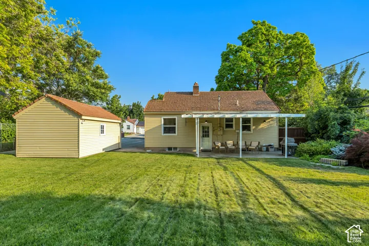 Expansive green lawn, detached storage building, covered patio, mature landscaping, and an exterior with siding