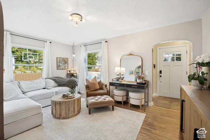 Hardwood flooring throughout, recessed archway entryway, multiple windows, and a flush mount ceiling light fixture