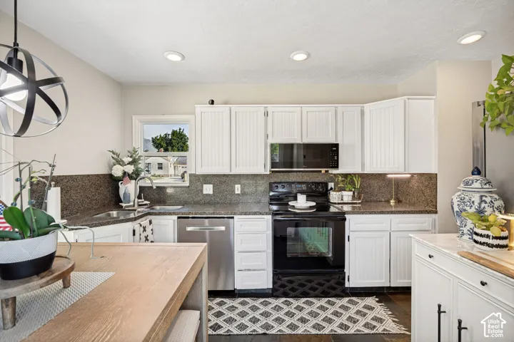 Kitchen featuring white cabinetry, dark stone countertops, stainless steel sink, and stainless steel dishwasher