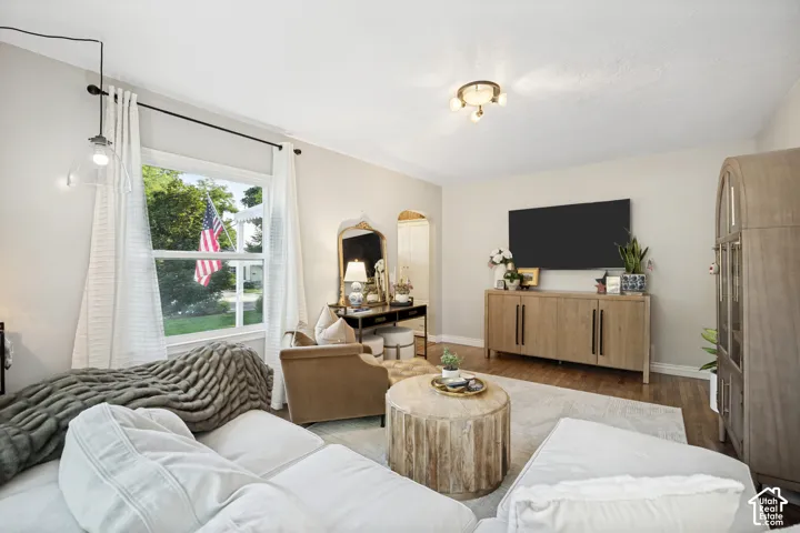 Bright living space featuring a window, wood-finish flooring, a contemporary ceiling light fixture, and neutral wall tones