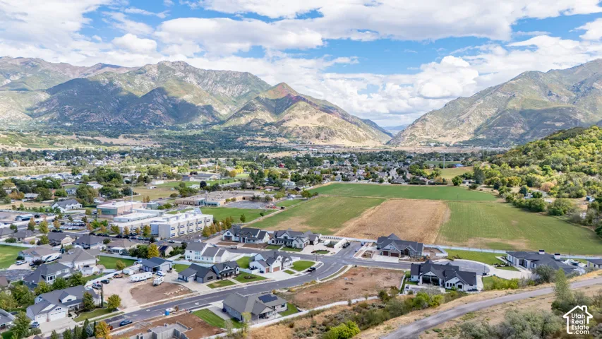 Expansive aerial perspective showcasing a residential development with surrounding mountainous terrain and agricultural fields