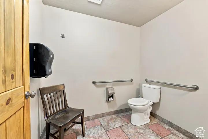 White commode with stainless steel grab bars