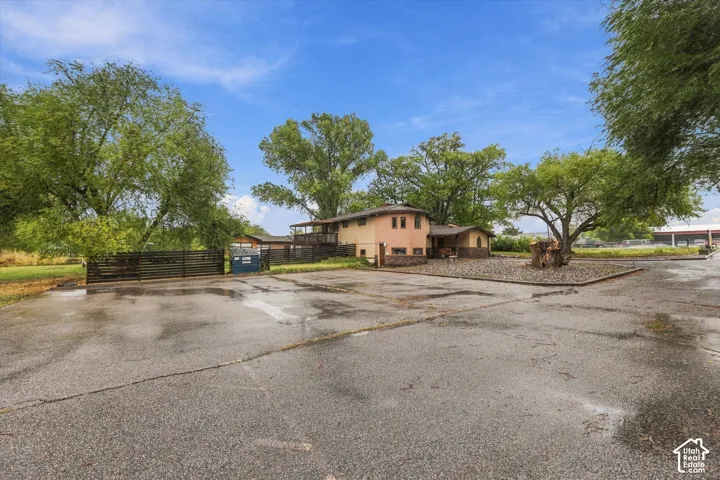 Asphalt parking area with an enclosed fence line and mature trees