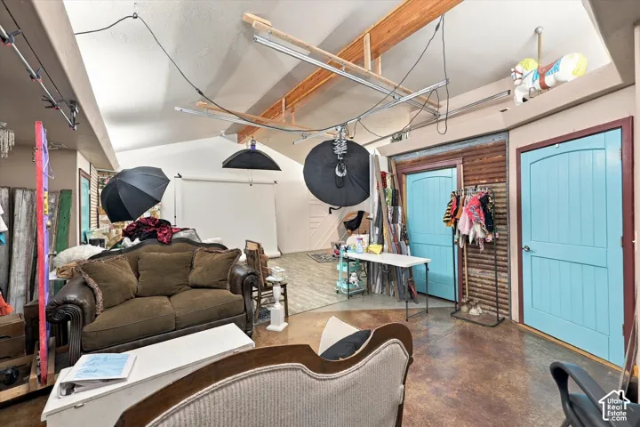 Vaulted ceiling, exposed wood beams, dual barn doors with blue finish, and polished concrete flooring