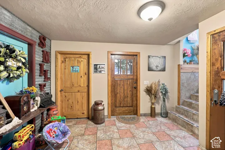 Stone tile flooring, wood panel doors, textured wall covering, wood trim, and a flush mount ceiling light fixture