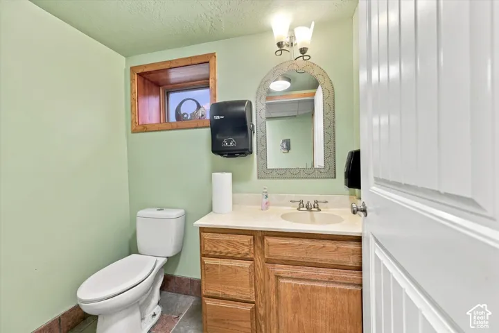 Bathroom featuring a wood-finish vanity with a light-colored countertop, an undermount sink, and a decorative mirror