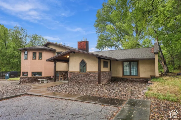 Stucco exterior with stone veneer accents, multi-pane arched windows, covered entry, and a gravel front yard