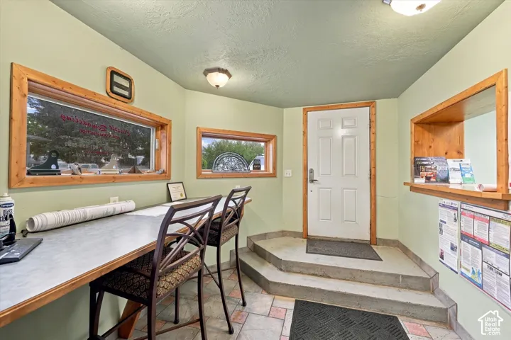 Reception area featuring a built-in counter, wood-trimmed windows, a service window with wood trim, a paneled entry door with wood trim, and multi-level tiled flooring